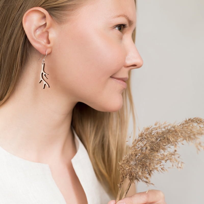 Woman looking right wearing wooden antler shape earrings