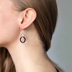 Naisen kaula ja korva, puu-mustat korvakorut, hiukset takana