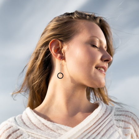 Woman with eyes closed, earring with black hoop hanging from the ear