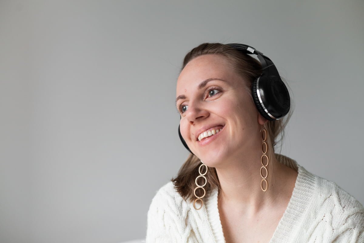 Nainen, jolla on suuret puukorvakorut, kuuntelee musiikkia kuulokkeilla