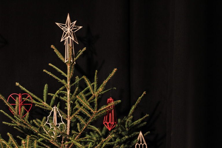 mustalla taustalla joulukuusi jossa puinen latvatähti ja koristee