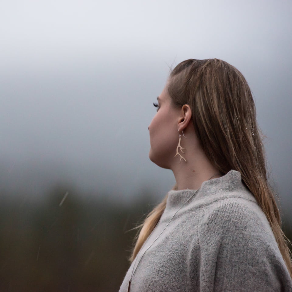 Woman looking viewing the landscape wearing antler earrings