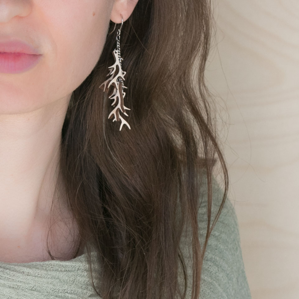 Brunette wearing wooden antler earrings