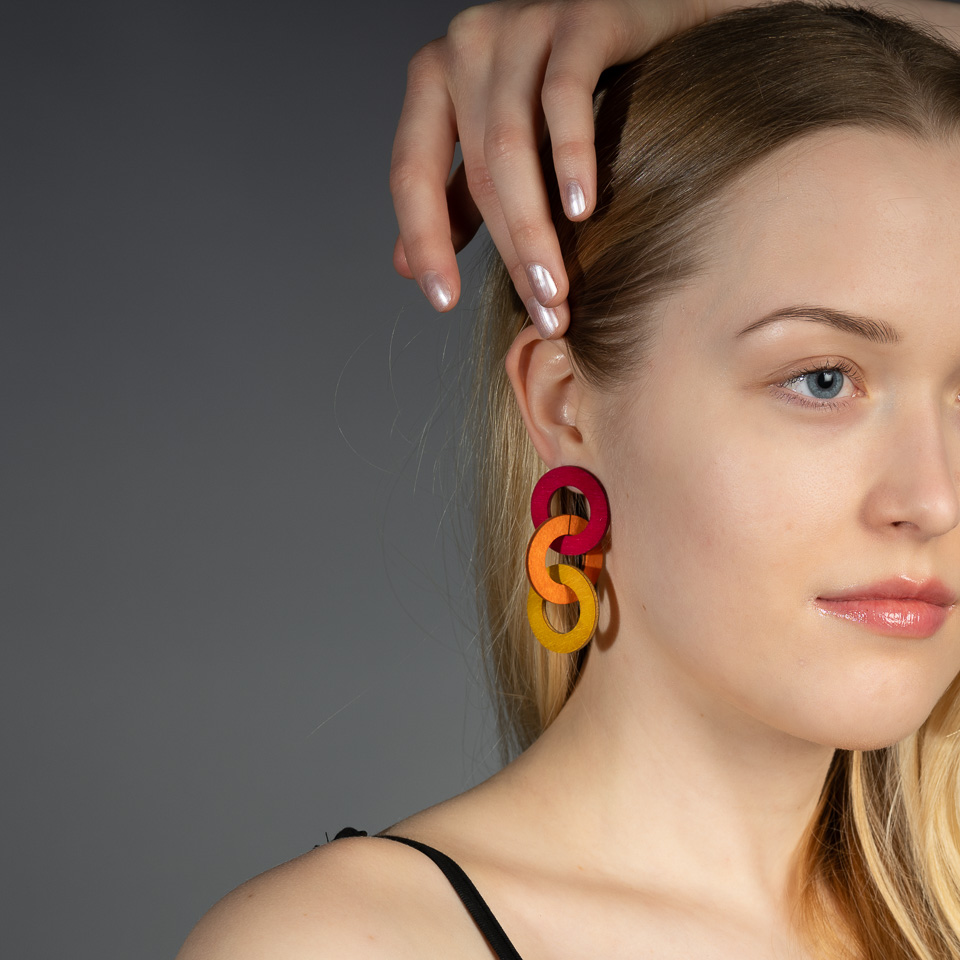 Värikkäät puiset ketjukorvakorut naisen korvassa