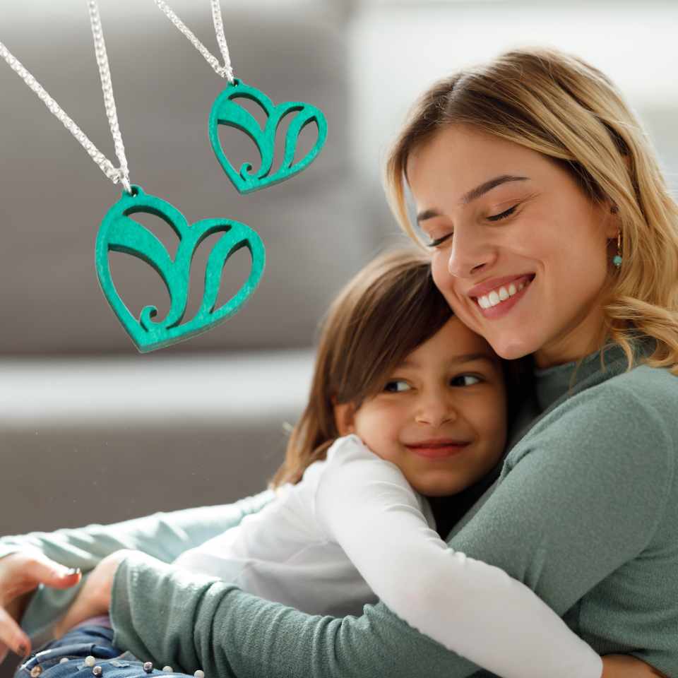 Mother daughter hugging with heart necklaces
