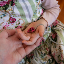 Hands holding me and mini me heart pendants