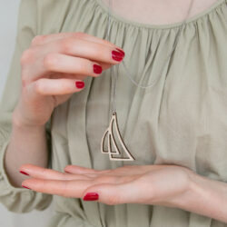 Kädet pitävät purjeiden mallista puukorua