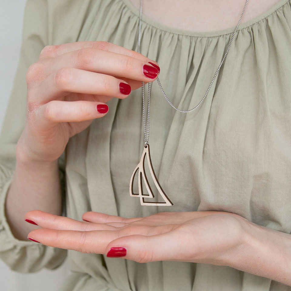 Kädet pitävät purjeiden mallista puukorua