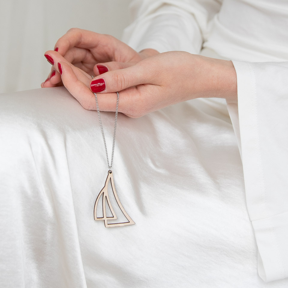 Nainen pitää kädessään purje-kaulakorua