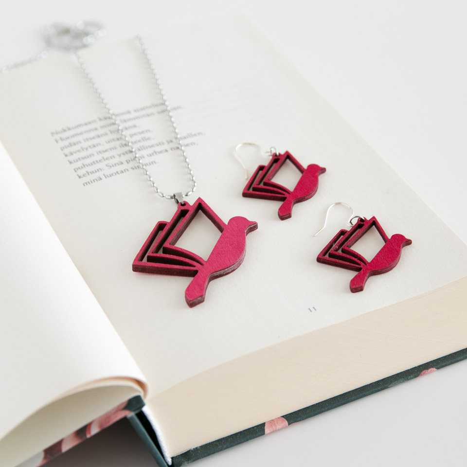 Roosan väriset kirjalintu korut kirjan päällä