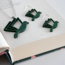 Vihreät kirjalintu-korvakorut ja kaulakoru kirjan päällä