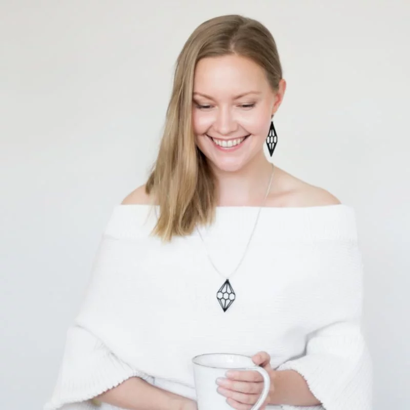 blond woman wearing wooden black diamong earrings and pendat