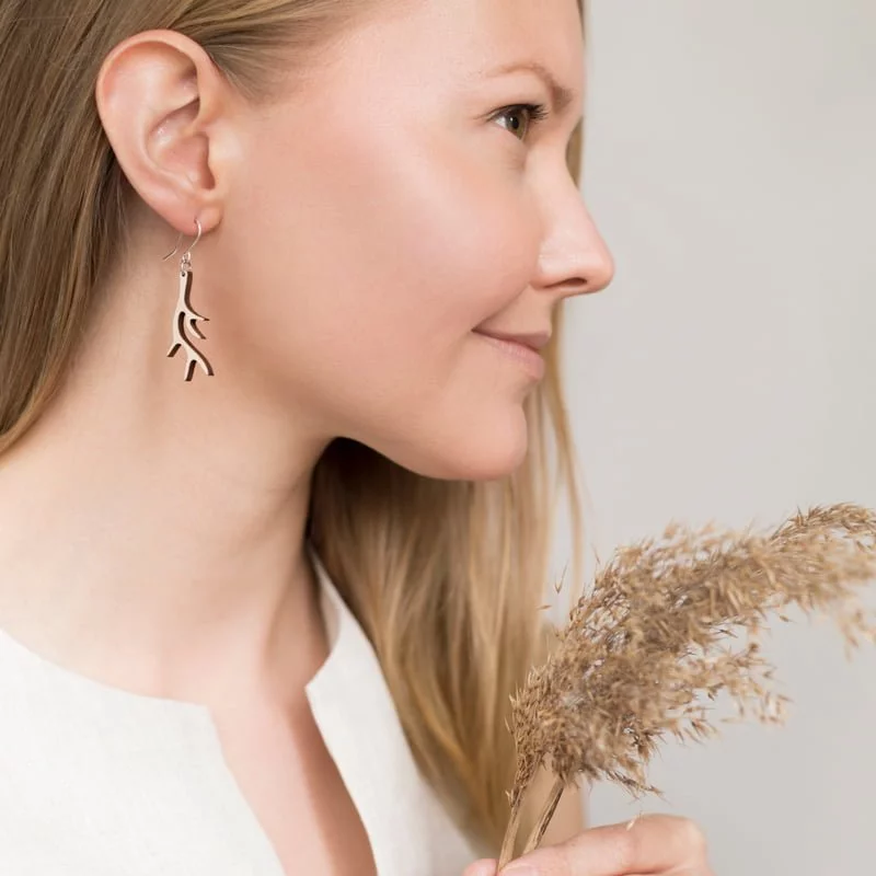Woman looking right wearing wooden antler shape earrings