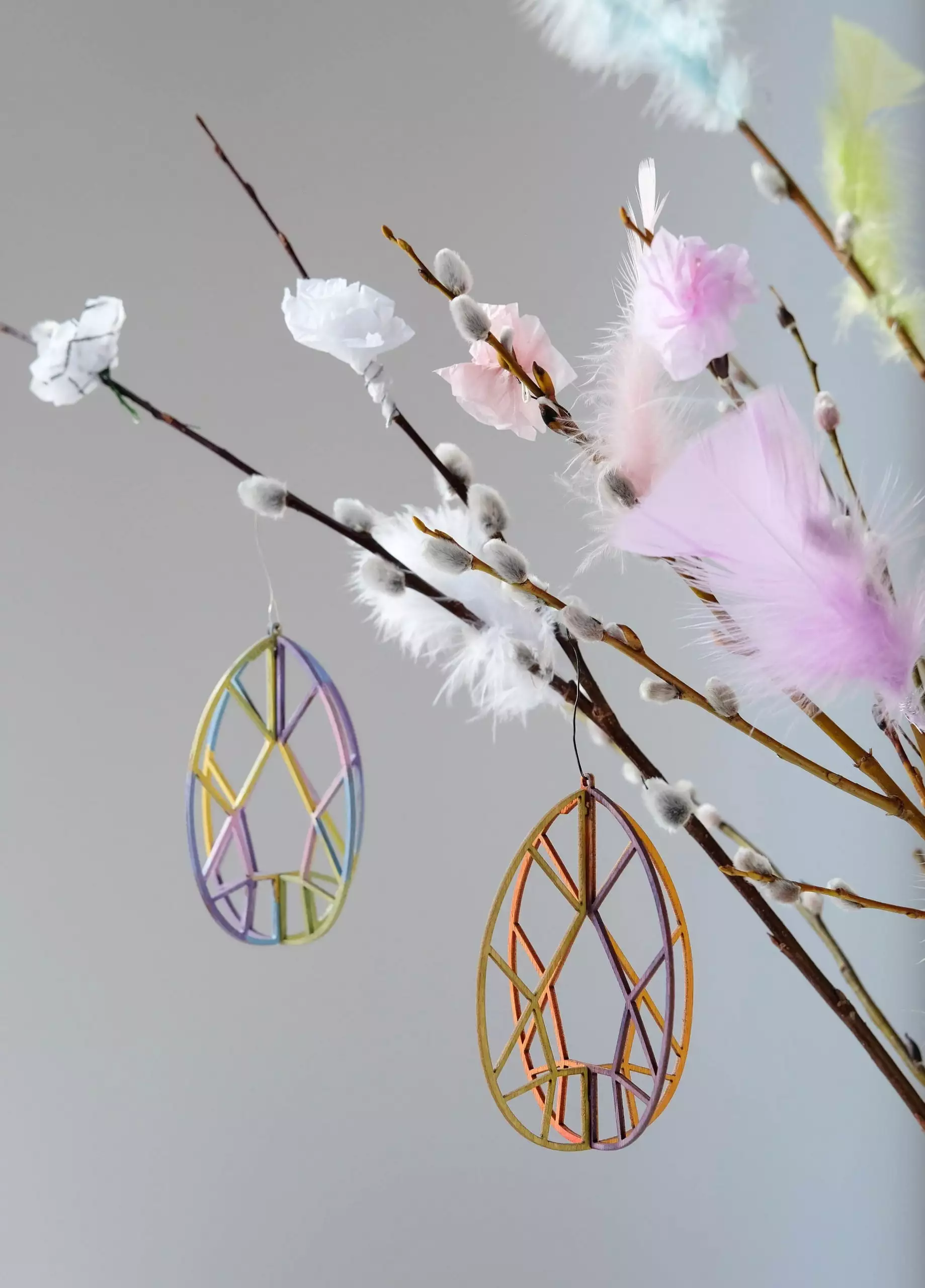 Värikkäitä pääsiäismunakoristeet roikkuvat virpomisvitsasta, jossa värikkäitä höyheniä.