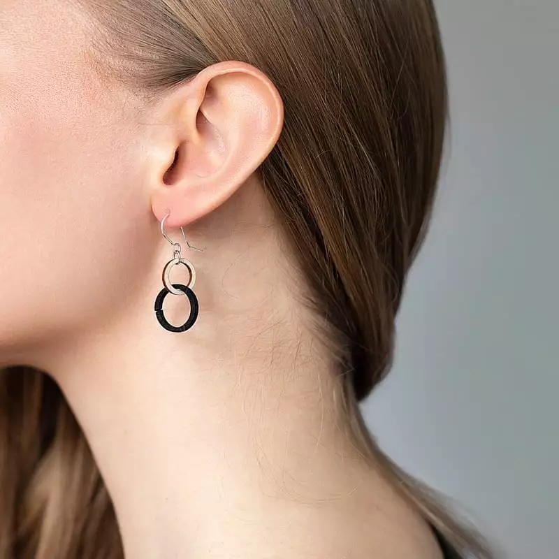 Naisen kaula ja korva, puu-mustat korvakorut, hiukset takana