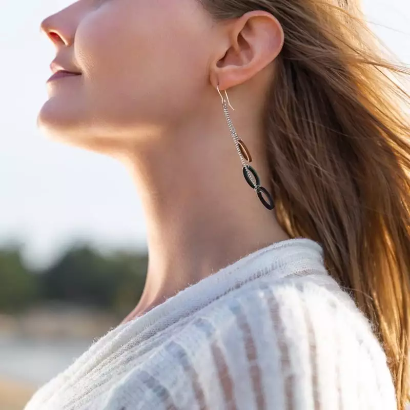 Woman with breeze in her hair, long earrings with metal chain and wooden hoops