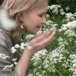 Woman with statement jewellery smelling flowers of the field
