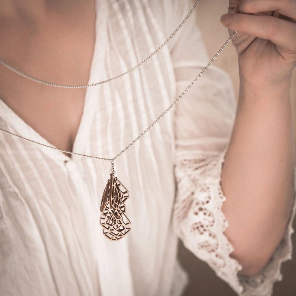 Woman in white holding wooden drop necklace