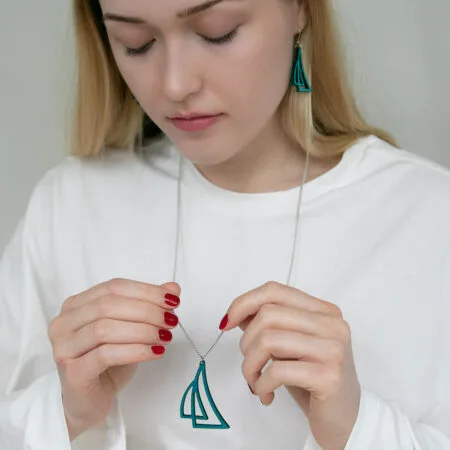 Nainen pitää käsissään purjevenekaulakorua