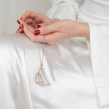 Nainen pitää kädessään purje-kaulakorua