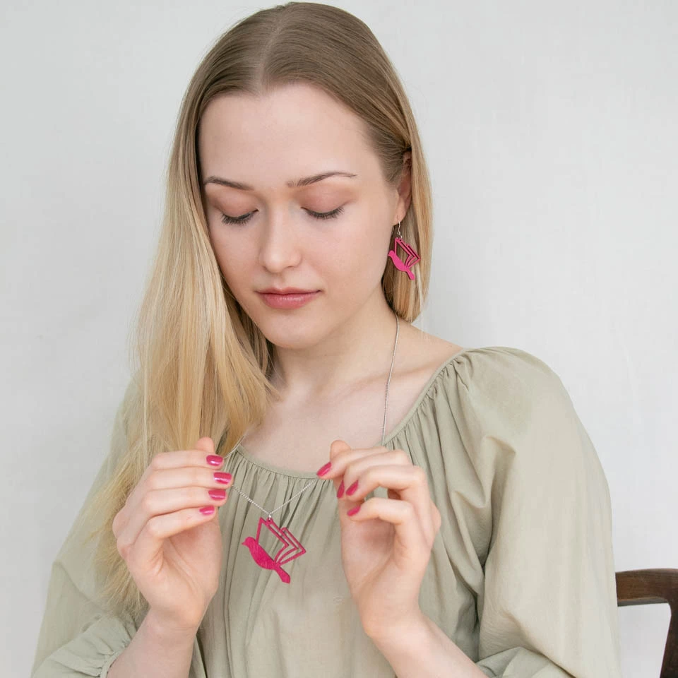 Nainen pitelee kirjalintu korua kädessään